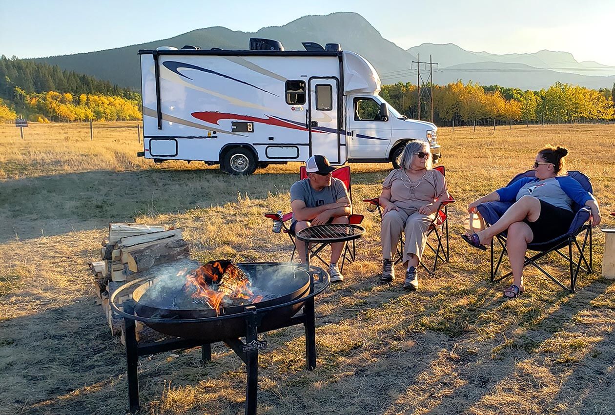 Family members enjoying a campfire in front of an RV