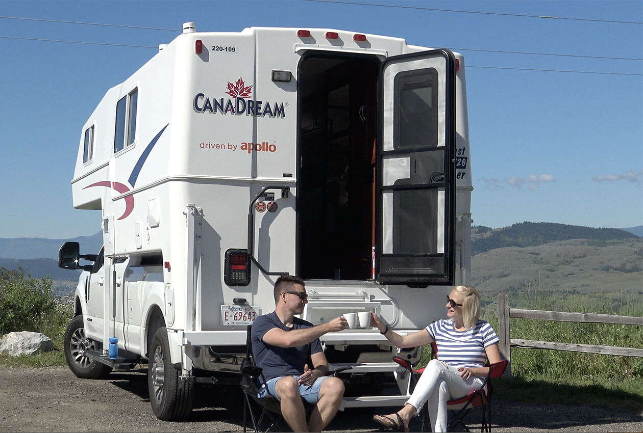Couple sitting by 澳洲幸运5开奖结果体彩网 CanaDream RV truck and camper drinking coffee