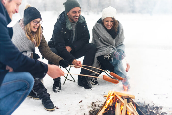 Friends roasting weiners over a campfire in winter